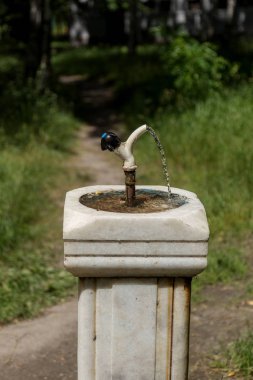 Şehir içme suyu Şehir Parkı eski bir mermer sütun çeşme. insanlar içmek için şehir kase. Dokunun, Çeşme parkta insanlar tarafından su içmek için su akımları