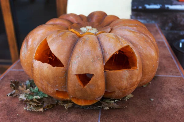 The scary face carved into a pumpkin devil head. Halloween pumpkin on the steps awful cafes, restaurants. Training at Halloween. Invitation to go to a cafe on a terrible feast of all impure forces