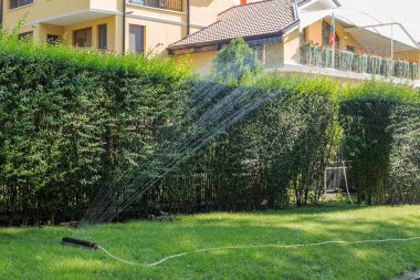 Bahçe sulama için modern aygıt. Sulama sistemi - bahçede sulama tekniği. Çim yağmurlama yeşil çim üzerinde su püskürtme. Otomatik Sprinkler Çim Sulama