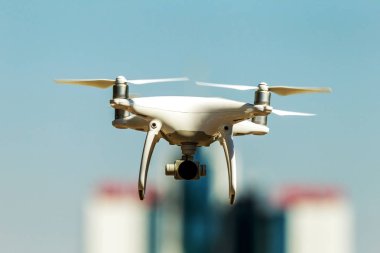 Kentsel binaların zemin üzerine şehir üzerinde parlak mavi gökyüzünde Quadrocopter insansız kamera hovers. Modern teknoloji fotoğraf ve video çekim kuşbakışı. Profesyonel karbon drone ile Gps