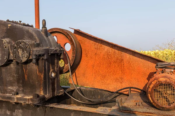 The old worn-out equipment oil rig. Old motor, belt drive, streaks of dirty engine oil in the worn-out equipment. Rusty metal