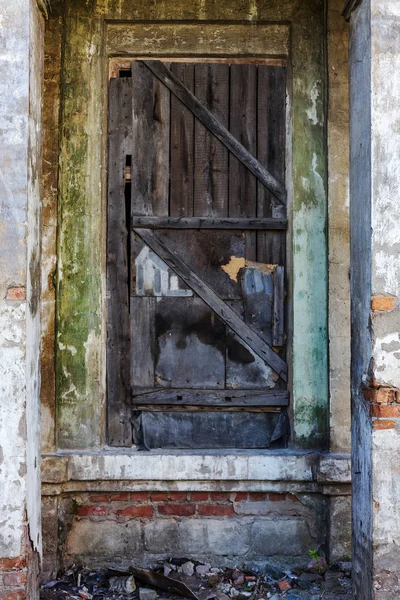 Old wooden door. Weathered cracked paint so old wooden door in wall of an ancient stone house in historical part of Odessa, Ukraine. An old stone wall with cement plastered old street entrance door