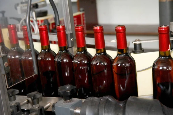 Production of industrial conveyor belt in the winery with glass bottles in the process of work and movement. Motion blur. Not without a sharp focus background for an industrial design