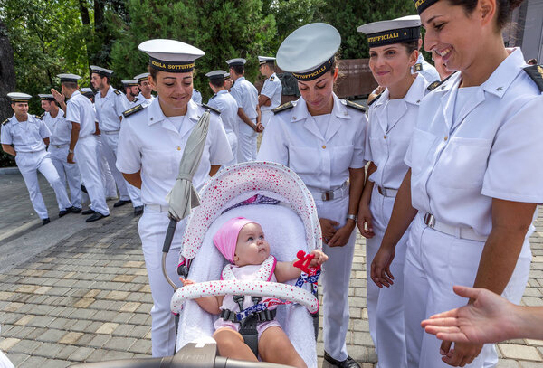 Odessa, Ukraine - August 16, 2016: Italian women sailors with interest the joy and play with the baby in a baby carriage on the Walk of Fame in Odessa. Women sailors are missing after their children.