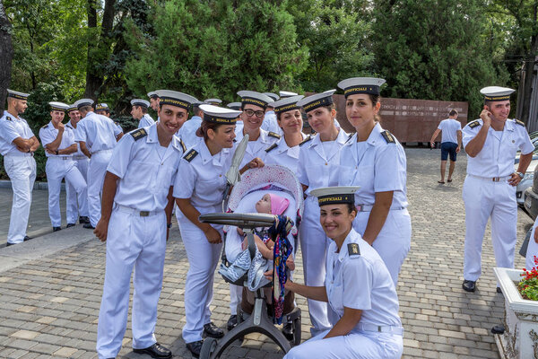 Odessa, Ukraine - August 16, 2016: Italian women sailors with interest the joy and play with the baby in a baby carriage on the Walk of Fame in Odessa. Women sailors are missing after their children.
