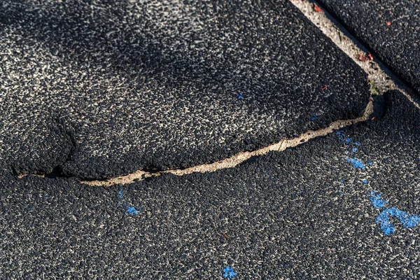 Very bad paved road. Cracks in the pavement, potholes. Very poor condition of local asphalt road after a low-quality patching
