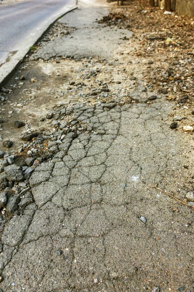 Bad road, damaged by rain and snow, needs repair. Broken asphalt coating leads to pothole, dangerous for vehicles and pedestrians. Bad emergency road. Dangerous road.  Destruction of roads, large cracks