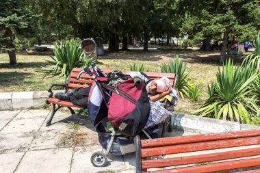 Varna, Bulgaristan - 1 Ağustos 2016: Evsiz uyur sıcak güneşin bir bankta sıcak yaz gününde en yoksul ülke Avrupa Birliği'ndeki şehir parkında