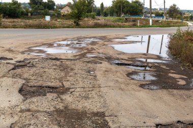 Çok kötü asfalt yol. Asfalttaki çatlaklar, çukurlar. Düşük kalitede bir yamadan sonra yerel asfalt yolunun durumu çok kötü