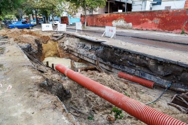 Odessa, Ukraine - September 29, 2016: Dug deep trench utilities engineering urban systems. Alarm system of urban sanitation and heating. Trench is filled with rusty dirty water erupted from pipeline. Repair work underground utilities clipart