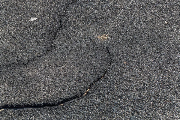 Very bad paved road. Cracks in the pavement, potholes. Very poor condition of local asphalt road after a low-quality patching