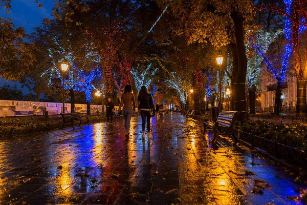 The ancient center of the city at night after rain. Night urban street with bright colored lights of street cafes and moving cars.