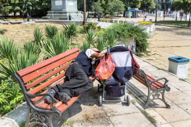 Varna, Bulgaristan - 1 Ağustos 2016: Evsiz uyur sıcak güneşin bir bankta sıcak yaz gününde en yoksul ülke Avrupa Birliği'ndeki şehir parkında