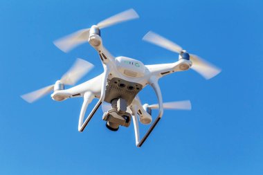 Kentsel binaların zemin üzerine şehir üzerinde parlak mavi gökyüzünde Quadrocopter insansız kamera hovers. Modern teknoloji fotoğraf ve video çekim kuşbakışı. Profesyonel karbon drone ile Gps