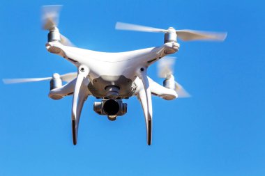 Kentsel binaların zemin üzerine şehir üzerinde parlak mavi gökyüzünde Quadrocopter insansız kamera hovers. Modern teknoloji fotoğraf ve video çekim kuşbakışı. Profesyonel karbon drone ile Gps