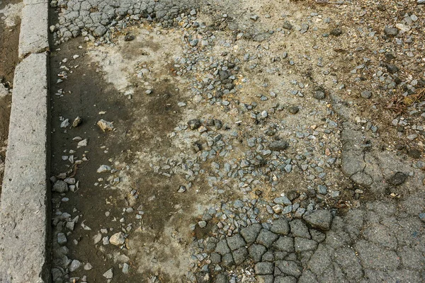 Bad road, damaged by rain and snow, needs repair. Broken asphalt coating leads to pothole, dangerous for vehicles and pedestrians. Bad emergency road. Dangerous road.  Destruction of roads, large cracks