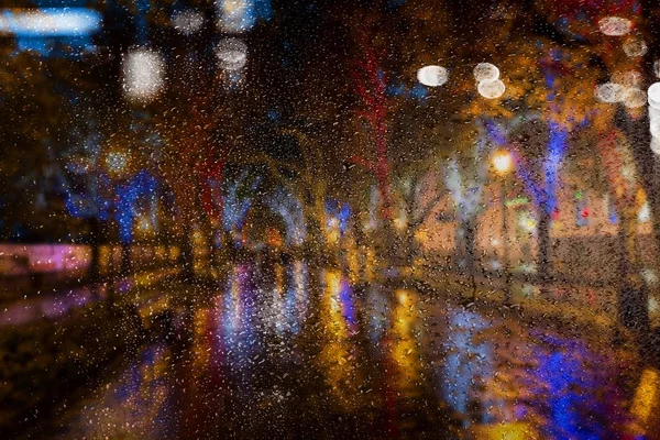 Blur night cityscape. The ancient center of the city at night after rain. Night urban street with bright colored lights of street cafes and moving cars. Motion blur, soft focus, stylization