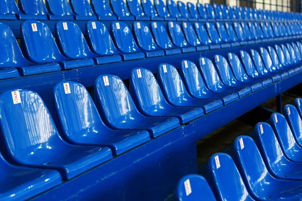 Blank old plastic chairs in the gym. Number of empty seats in a small sports complex. New Rows of plastic seats for fans. Shallow depth of field perspective, soft focus