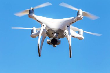 Kentsel binaların zemin üzerine şehir üzerinde parlak mavi gökyüzünde Quadrocopter insansız kamera hovers. Modern teknoloji fotoğraf ve video çekim kuşbakışı. Profesyonel karbon drone ile Gps