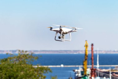 Kentsel binaların zemin üzerine şehir üzerinde parlak mavi gökyüzünde Quadrocopter insansız kamera hovers. Modern teknoloji fotoğraf ve video çekim kuşbakışı. Profesyonel karbon drone ile Gps