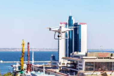 Kentsel binaların zemin üzerine şehir üzerinde parlak mavi gökyüzünde Quadrocopter insansız kamera hovers. Modern teknoloji fotoğraf ve video çekim kuşbakışı. Profesyonel karbon drone ile Gps