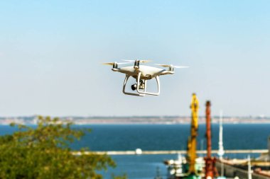 Kentsel binaların zemin üzerine şehir üzerinde parlak mavi gökyüzünde Quadrocopter insansız kamera hovers. Modern teknoloji fotoğraf ve video çekim kuşbakışı. Profesyonel karbon drone ile Gps