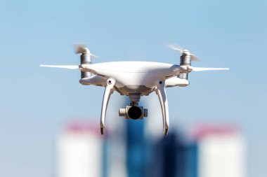 Kentsel binaların zemin üzerine şehir üzerinde parlak mavi gökyüzünde Quadrocopter insansız kamera hovers. Modern teknoloji fotoğraf ve video çekim kuşbakışı. Profesyonel karbon drone ile Gps