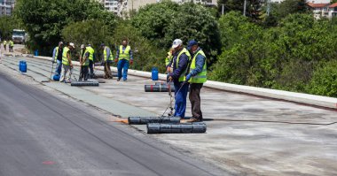 Varna, Bulgaristan - 20 Haziran 2017: yalıtım malzemesi onarım sırasında köprünün karayolu su yalıtımı, çatı kaplama, inşaat site yükler rulo, inşaat işçisi. Membran su yalıtımı kaynak sırasında alev
