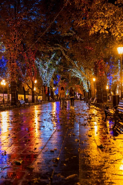 The ancient center of the city at night after rain. Night urban street with bright colored lights of street cafes and moving cars.