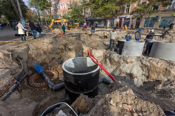 Odessa, Ukraine - September 29, 2016: Dug deep trench utilities engineering urban systems. Alarm system of urban sanitation and heating. Trench is filled with rusty dirty water erupted from pipeline. Repair work underground utilities