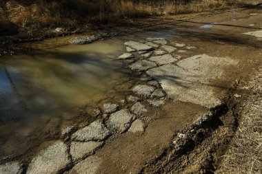 Çok kötü asfalt yol. Asfalttaki çatlaklar, çukurlar. Düşük kalitede bir yamadan sonra yerel asfalt yolunun durumu çok kötü