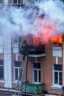  Bir yangında bir apartman. Güçlü parlak ışık ve kulüpleri, duman bulutları pencere yanan ağırlıyorlar. İtfaiyeciler evde yangın söndürmek. Yangın merdivenleri üzerinde çalışmak