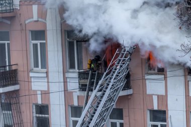  Bir yangında bir apartman. Güçlü parlak ışık ve kulüpleri, duman bulutları pencere yanan ağırlıyorlar. İtfaiyeciler evde yangın söndürmek. Yangın merdivenleri üzerinde çalışmak