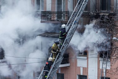  Bir yangında bir apartman. Güçlü parlak ışık ve kulüpleri, duman bulutları pencere yanan ağırlıyorlar. İtfaiyeciler evde yangın söndürmek. Yangın merdivenleri üzerinde çalışmak