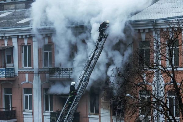 A fire in an apartment building. Strong bright light and clubs, smoke clouds window of their burning house. Firefighters extinguish fire in house. Work on fire stairs