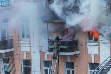 Odessa, Ukrayna - 29 Aralık 2016: Bir binanın içinde bir ateş. Güçlü parlak ışık ve kulüpleri, duman bulutları pencere yanan ağırlıyorlar. İtfaiyeciler evde yangın söndürmek. Yangın merdivenleri üzerinde çalışmak