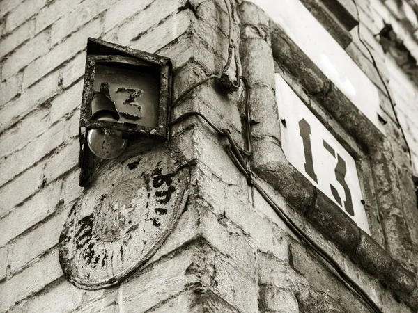 Old rusty broken house number 13 with street lamp. Old retro weathered painted cast iron plate with number 13, authentic architectural background. Number 13 on stone wall to indicate the house number