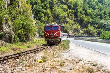 Bansko, Bulgaristan -29 Temmuz 2016: küçük retro rock Tren Garı yolcu sırt boyunca geçmiş dağ yolu virajlı yıpranmış eski dar hat raylar üzerinden taşır