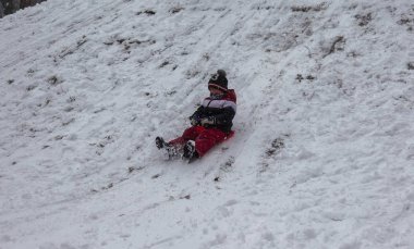 Odessa, Ukrayna - 24 Şubat 2018: Güçlü kar yağışı, şehrin sokaklarında siklon. Mutlu çocuk bir kızak dağdan binmek. Kar yağışı, frost. Kış aylarında bir eğlence parkı. Çocuk iyi eğlenceler
