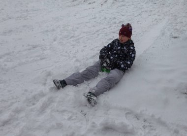 Odessa, Ukrayna - 24 Şubat 2018: Güçlü kar yağışı, şehrin sokaklarında siklon. Mutlu çocuk bir kızak dağdan binmek. Kar yağışı, frost. Kış aylarında bir eğlence parkı. Çocuk iyi eğlenceler
