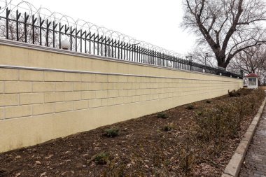 bir koruma alanı çevreleyen modern taş duvar. tuğla yeni modern pahalı sokak çit sokaklarda. Duvar çit Seksiyonel kabarık yol macun ile sıvalı. Duvar dikenli tel çit ile