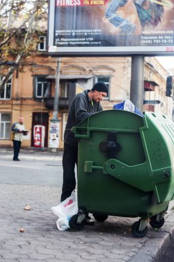 Odessa, Ukrayna - 20 Ekim 2015: çöp kutuları boş şişeler ve gıda artıkları arayan yakınındaki evsiz serseriler. Evsizler sorunu. Dilenciler - işsiz, mülteciler, göçmenler