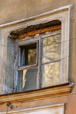Zavallı çeyreğinde konut binasının kirli, yıkık duvar ahşap çerçeve ile eski bir pencere. Yıkım ve yoksulluk yaratıcı arka plan. Eski ahşap kırık pencere yıpranmış binanın duvarındaki