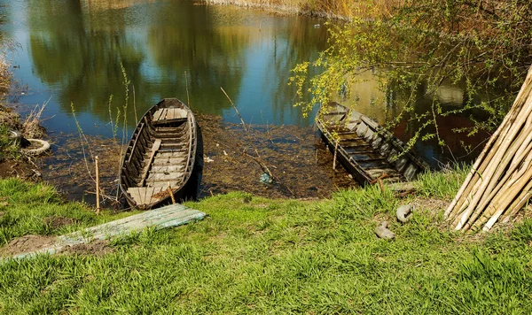 古い木造青ボート釣りボートの草に覆われた湖チャネルの美しい春の晴れた日 中央レーンの典型的な風景 湖の岸に葦で釣りボート — ストック写真