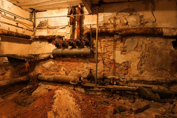 地下室的旧锅炉房锅炉房的旧控制中心 有管道和圆形水龙头 废弃的工业建筑内部 旧损坏的锅炉房 老生锈的管道工业 — 图库照片