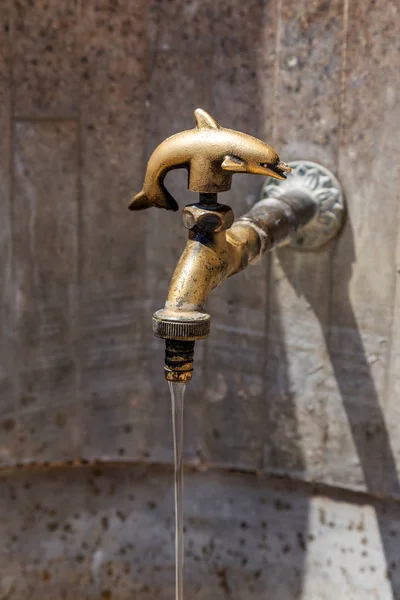 Ancient decorative tap. An old stylized vintage bronze faucet on the public street water pipe, a source of clean water for the population, Varna, Bulgaria