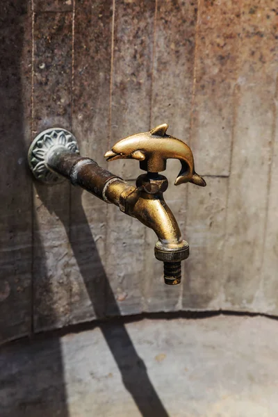 Ancient decorative tap. An old stylized vintage bronze faucet on the public street water pipe, a source of clean water for the population, Varna, Bulgaria