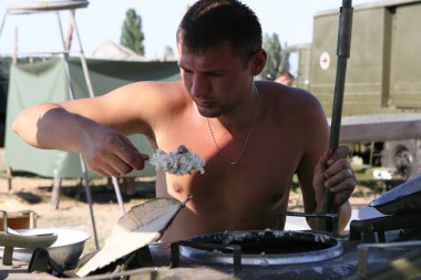 ODESSA, UKRAINE - August 23, 2007: Archive. Ukrainian army feeds on field military kitchen during liquidation of large-scale forest fires during drought. Military field kitchen of Second World War clipart