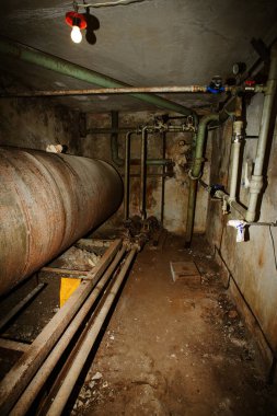 eski kazan dairesinde ıslak Bodrum. Endüstriyel bir binanın terk edilmiş iç. eski kazan dairesi zarar görmüş. Eski paslı boruları. Paslı metal borular delik, mekanizmaları, paslı çalışma dışı elektrik motoru ile
