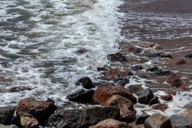 Granit taş kõyõ alanlarõ ve akış aşağı kum Beach sakin mola sırasında yumuşak küçük dalgalar. Dalga deniz köpük buzlu karşı bozuldu. Dalga düşme ve çöl beac kıyısında boyunca akar